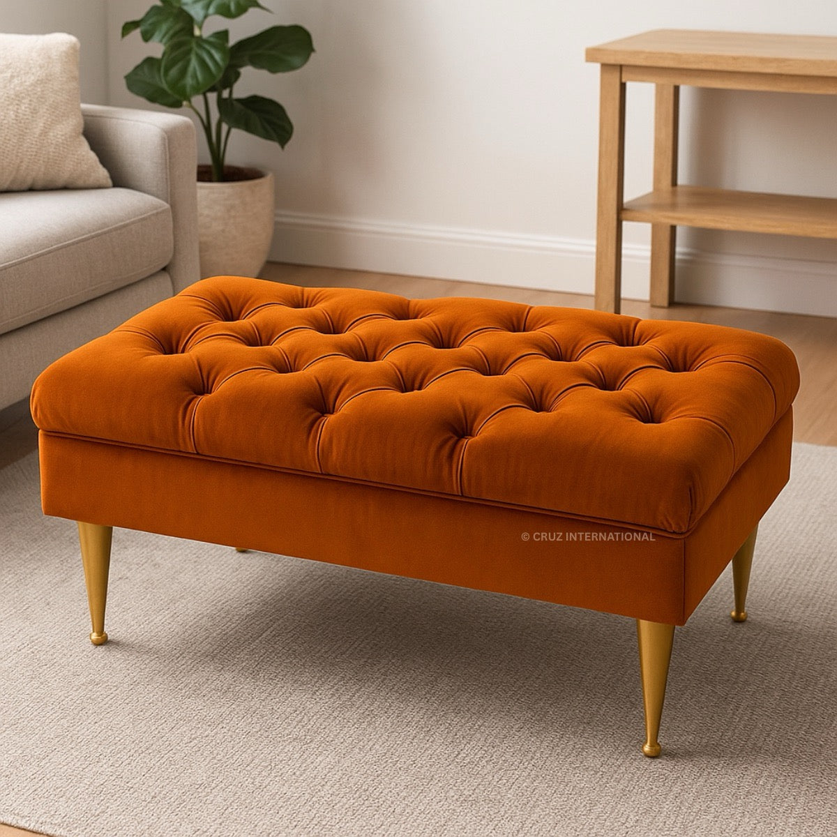 Orange tufted ottoman with gold legs in a living room setting.